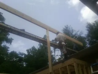 Carpenter setting a ridge beam over a new addition frame — Ice Dam Removal by Roofing Brothers in Leggett