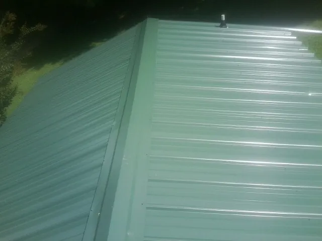 New green metal panels meeting at the ridge of a roof — Flat Roof Repair work by our crew in Leggett
