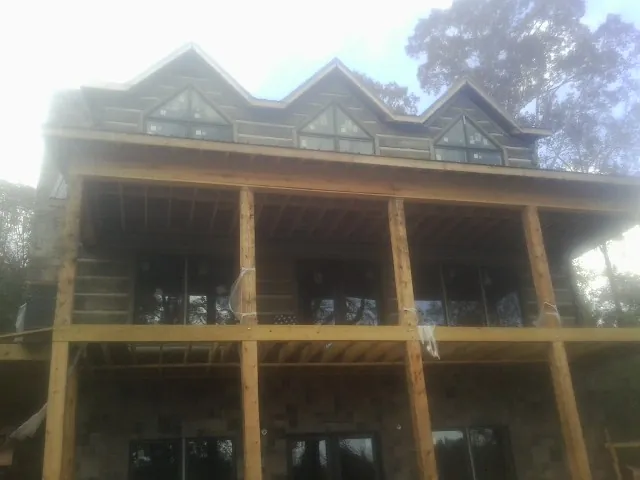 Dormers and porch framing on a large log home under construction — Roof Coating work by our crew in Leggett