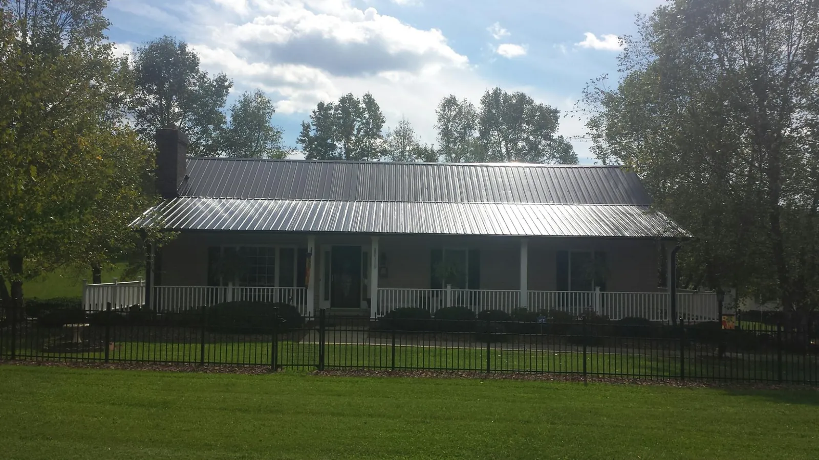 Gray metal roof on a brick ranch with a full width front porch — Gutter Guard Installation work by our crew in Leggett