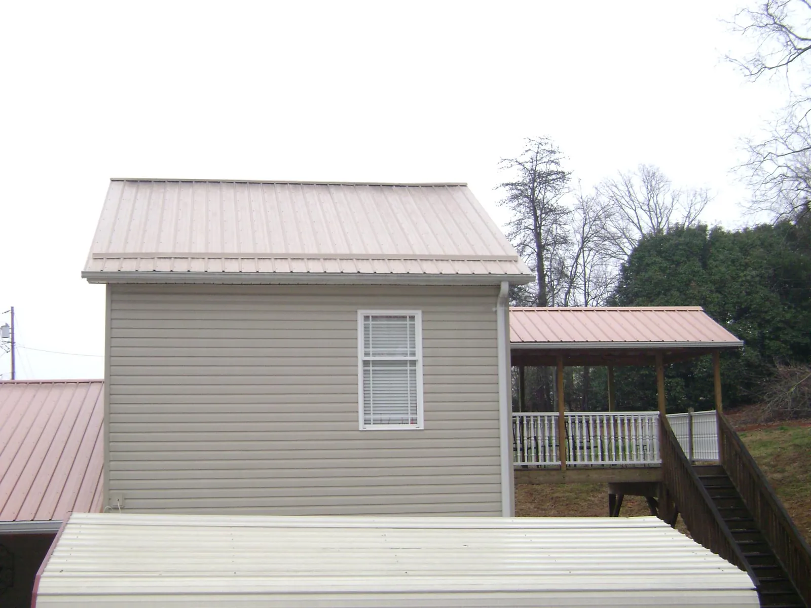 Tan metal roofs on a two story addition and attached porch, from a Roof Replacement job in Leggett