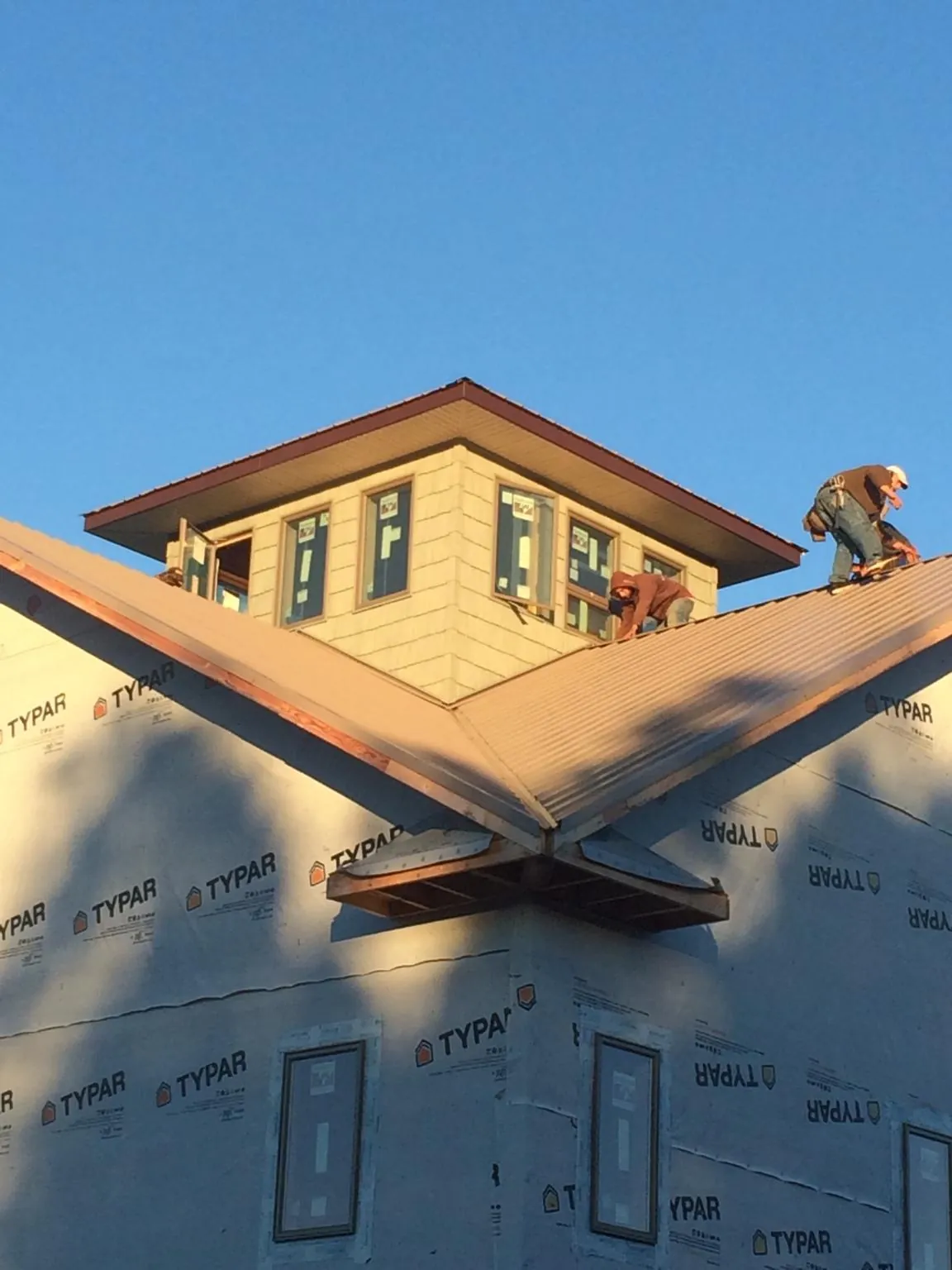 Roofers working around a rooftop cupola on a new metal roof at sunset — Roof Waterproofing in Leggett by Roofing Brothers